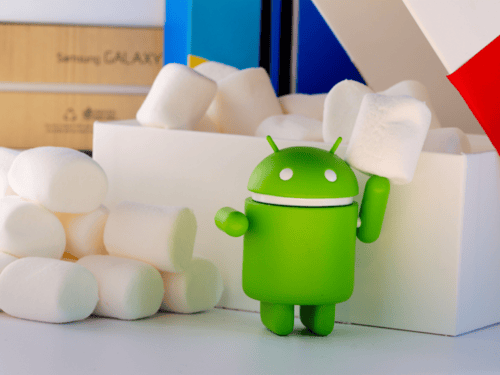 Mascotte Android tenant un marshmallow, entourée de guimauves et de boîtes colorées