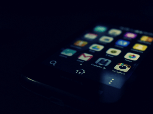Smartphone display with various app icons visible, including Gmail and Instagram, highlighting a dark theme interface.