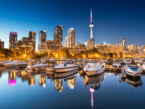 Vue nocturne de la skyline de Toronto avec des bateaux amarrés et la tour CN éclairée en arrière-plan