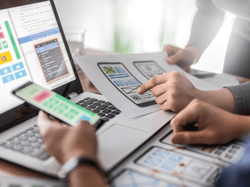 Designing a mobile application with mockups and code on a laptop and a smartphone